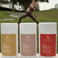 Three bottles of beauty by earth magnesium deodorant with a blurred background of a person exercising outdoors.
