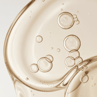 Close-up of golden liquid with bubbles on a light gray background