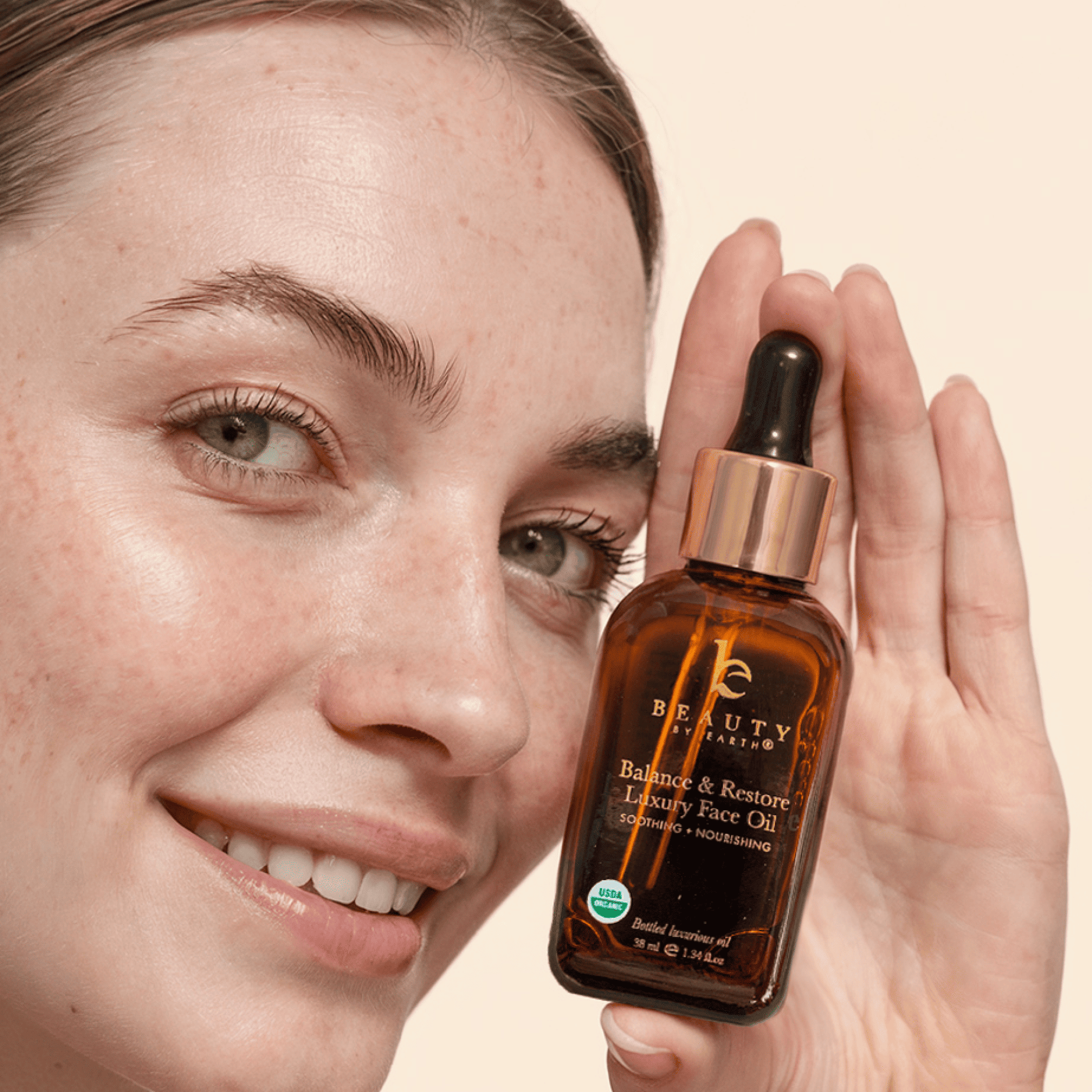 Person holding a bottle of 'Balance & Restore' luxury face oil with a beige background