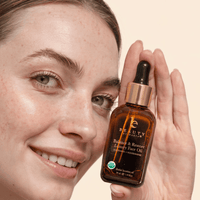 Person holding a bottle of 'Balance & Restore' luxury face oil with a beige background