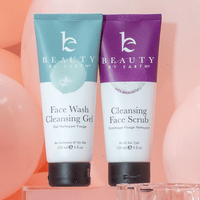 Two tubes of 'Beauty by Earth' face wash and cleansing scrub on a pink background