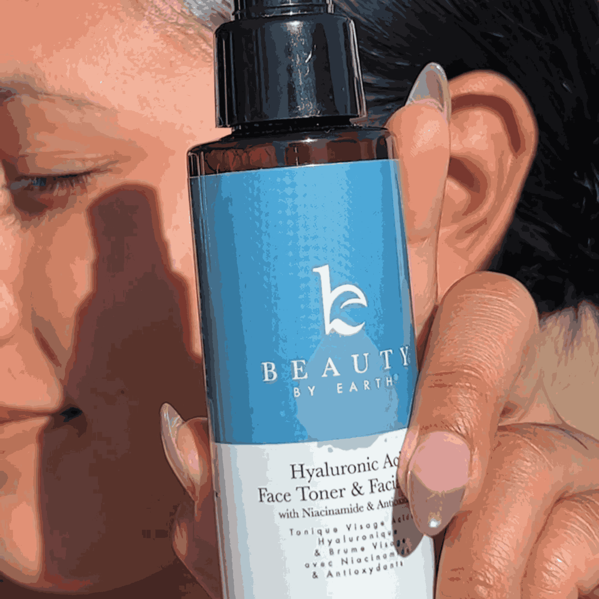 Hand holding a bottle of 'Beauty by Earth' toner with a blue label.