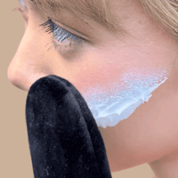 Close-up of a person applying white self tanning lotion for face  with a neutral background.