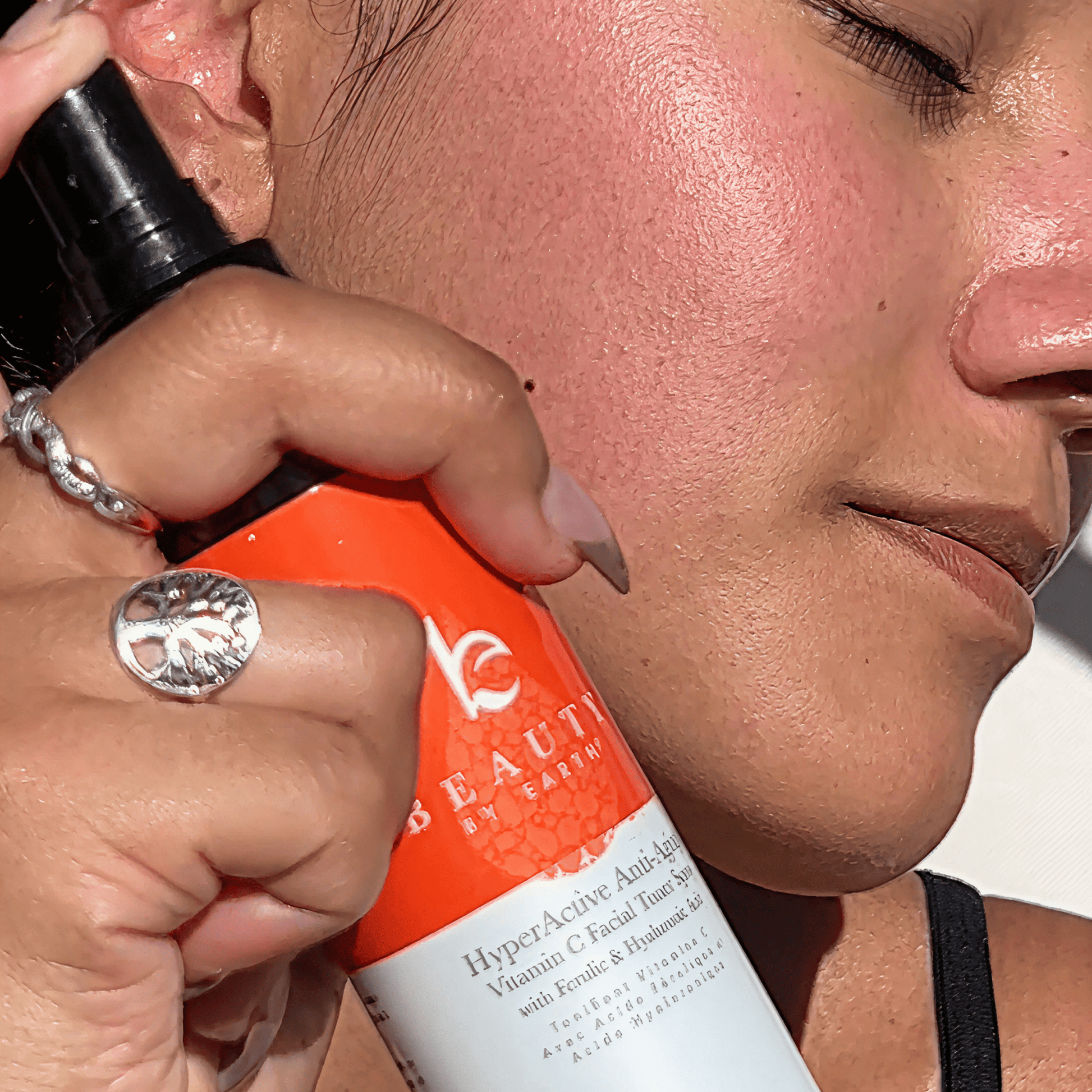 Person applying a skincare product to their face with a bottle labeled 'Vc Beauty'.