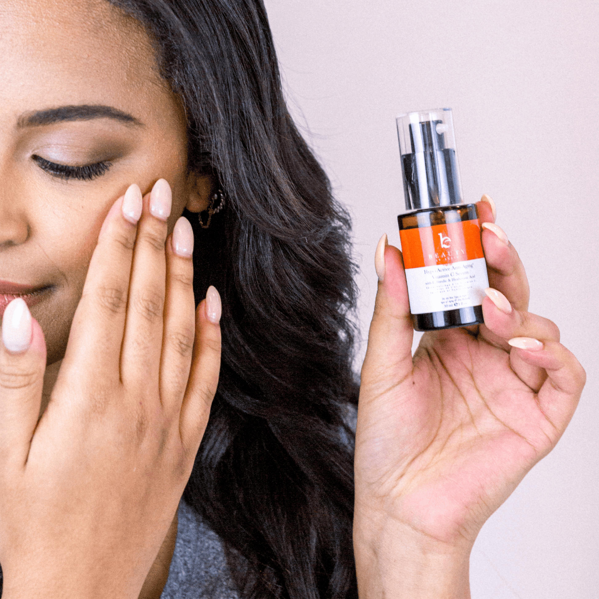 Woman holding a skincare serum bottle with a neutral background