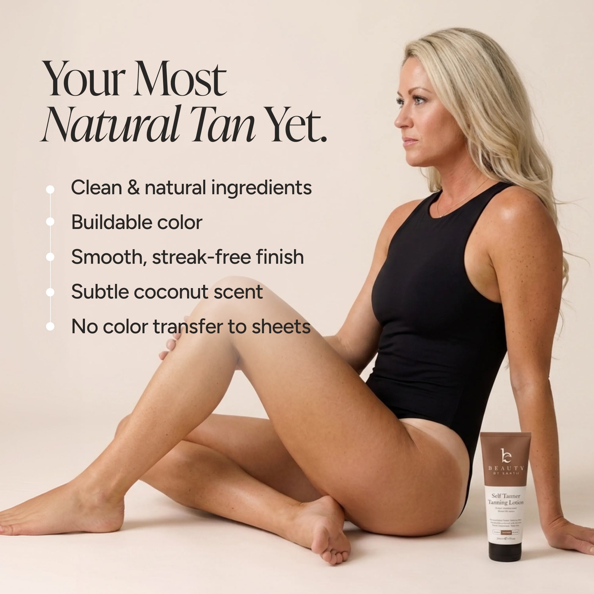 A woman in a black bodysuit sits on a light beige floor next to a tube of Beauty By Earth Self Tan lotion.