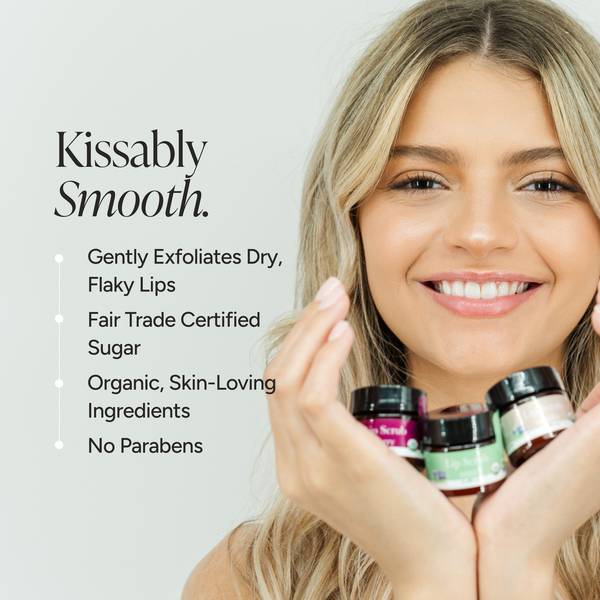 Blonde woman poses with 3 lip scrubs on her hand. Benefit bullet points:: kissably smootnh.