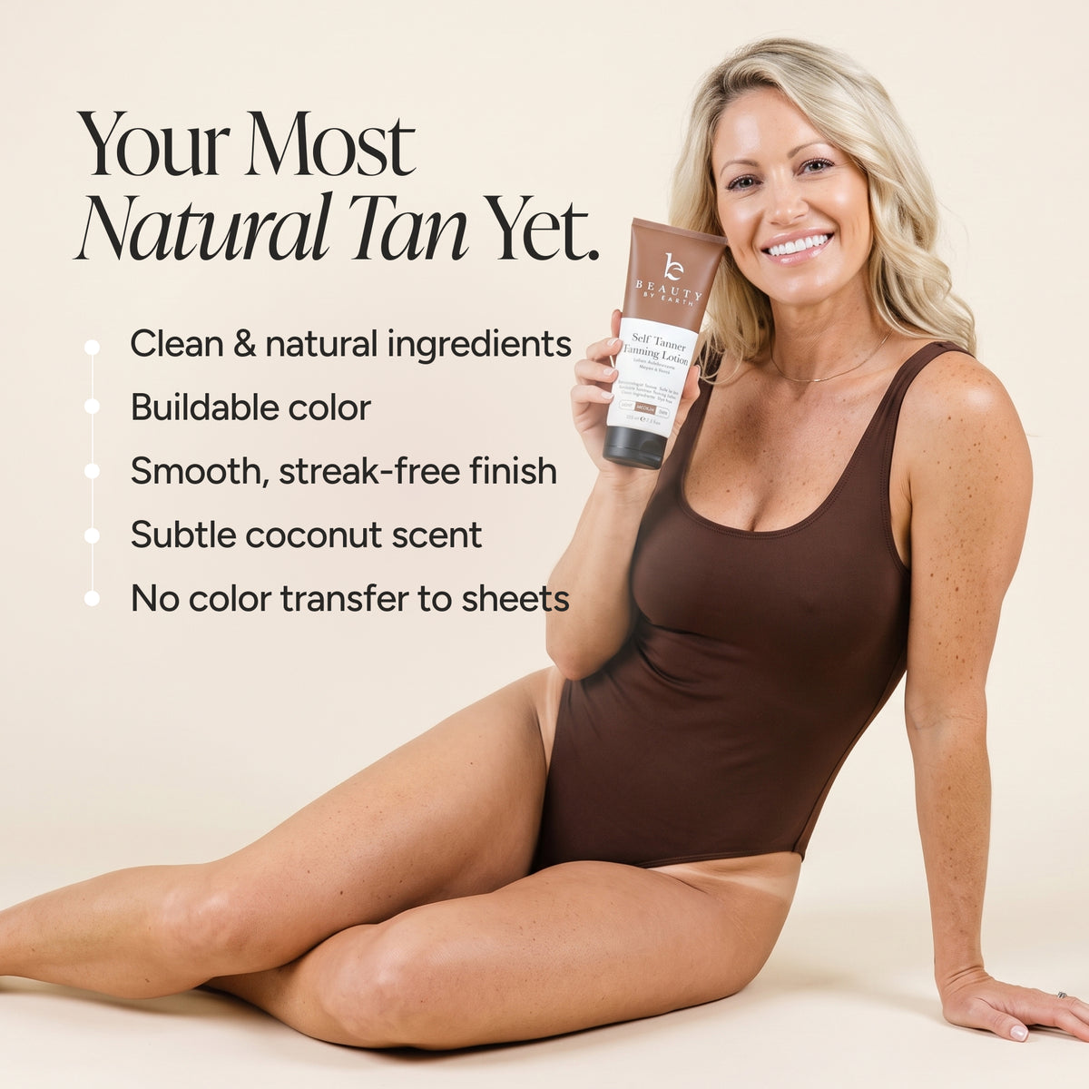 A woman in a brown bodysuit sits on a beige studio background holding a tube of Beauty By Earth Self Tannin Lotion Text on the left reads 'Your Most Natural Tan Yet.