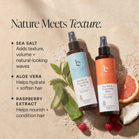 Two sea salt spray bottles on a textured beige background with promotional text. The bottles are Sea Salt & Texturizing Spray in Ocean Waves and Citrus Breeze scents, styled with aloe vera, raspberries, coconut, and citrus slices.