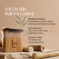 A bamboo-handled brush in a matching bamboo holder, shown on a warm beige background with text callouts about bamboo handle, PBT bristles, and cruelty-free quality.