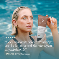 A woman in a swimming pool holds up a brown and white tube of Beauty by Earth Self Tanner Tanning Lotion.