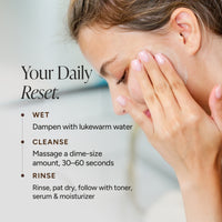 Close-up of a woman touching her face with her fingers, with text on the left reading 'Your Daily Reset.' and bullet points for wet, cleanse, and rinse steps.