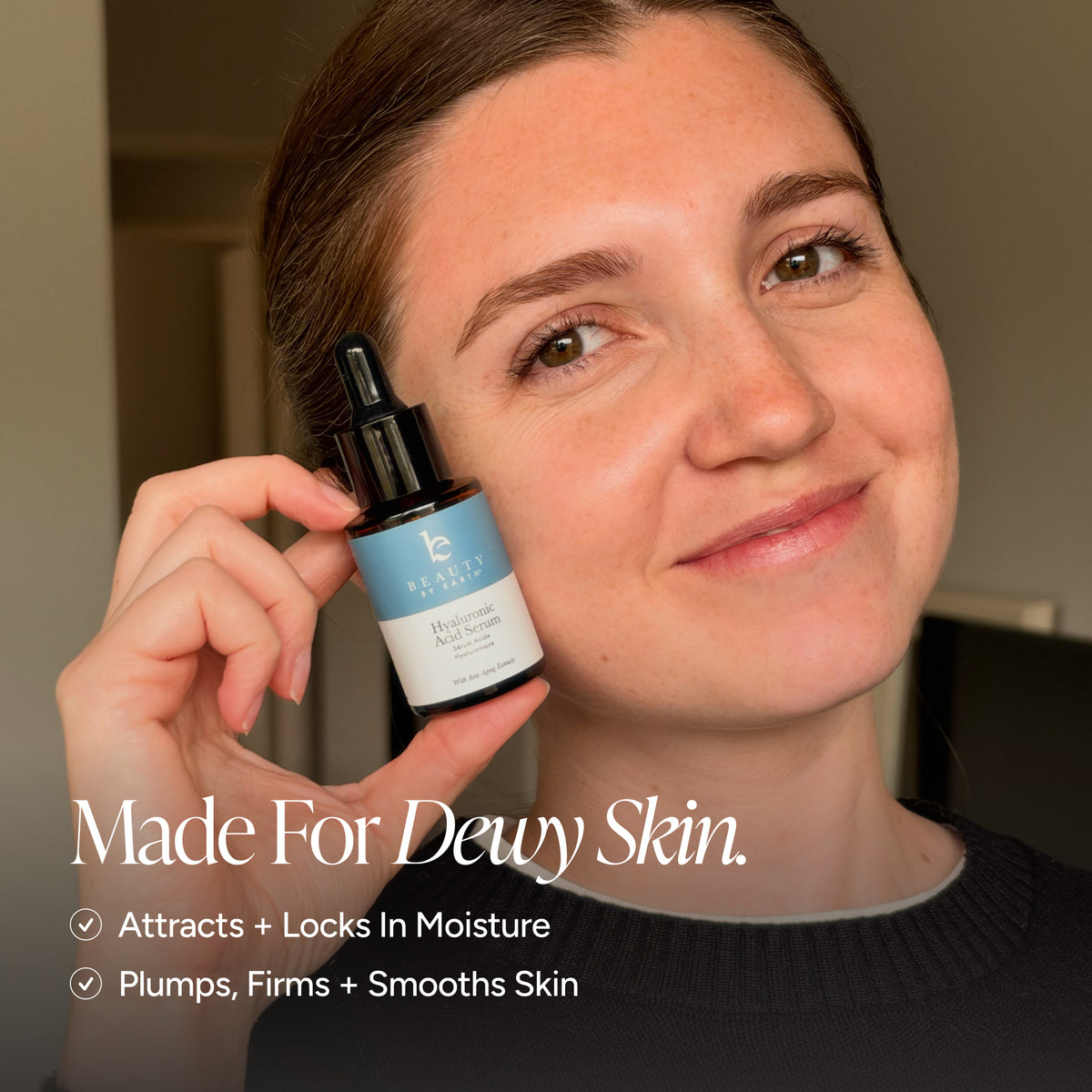 Woman with dewy skin holds a bottle of Beauty by Earth Hyaluronic Acid Moisturizer.