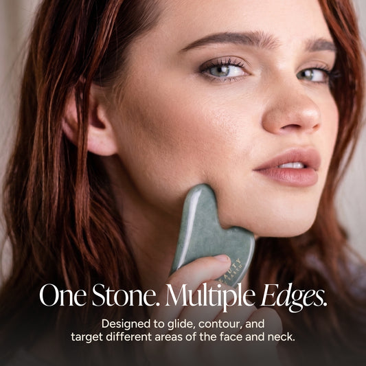 A close-up of a woman holding a green jade facial massage tool against her jawline, with text reading 'One Stone. Multiple Edges.