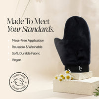 A black mitt on a stone pedestal with small white daisies, alongside marketing text reading 'Made To Meet Your Standards.' and a circular cruelty-free seal.