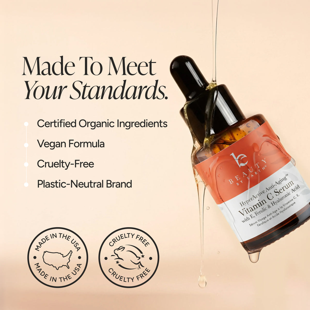 Beauty By Earth Vitamin C Serum in an amber glass dropper bottle with a black dropper cap, shown on a warm beige background with marketing text and circular 'Made in the USA' and 'Cruelty Free' badges.