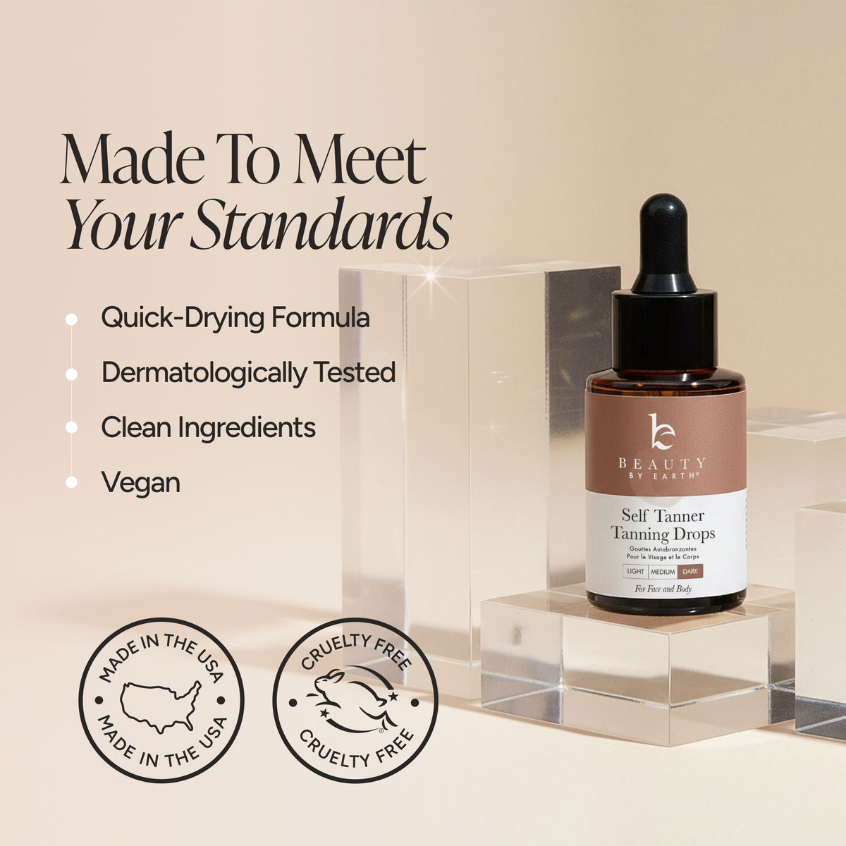 Beauty by Earth Self Tanner Tanning Drops bottle displayed on clear acrylic blocks against a warm beige background, with marketing text and circular 'Made in the USA' and 'Cruelty Free' badges.