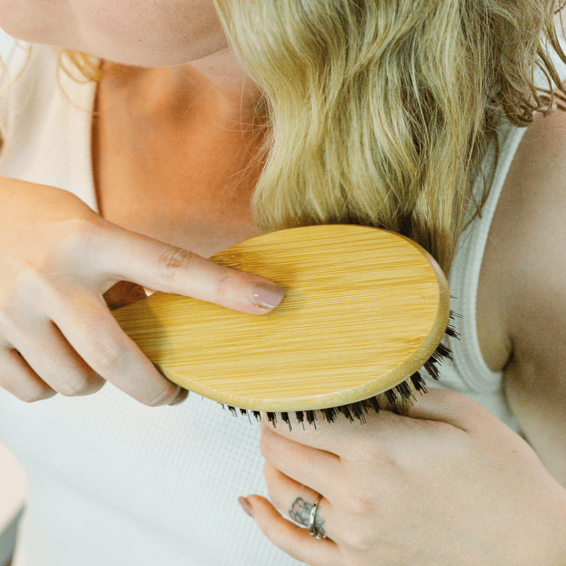 Person using a wooden hairbrush on another person's hair