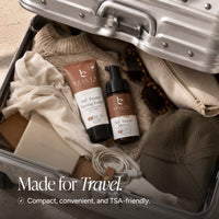 Self-tanner products arranged inside an open silver suitcase with travel items, including a sweater, sunglasses, a cap, a pouch, and a phone cable. Text at the bottom reads, 'Made for Travel.
