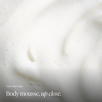 Close-up of white body mousse with small bubbles and the text 'THE TEXTURE Body mousse, up close.'