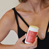 Person holding a container of magnesium deodorant against a neutral background