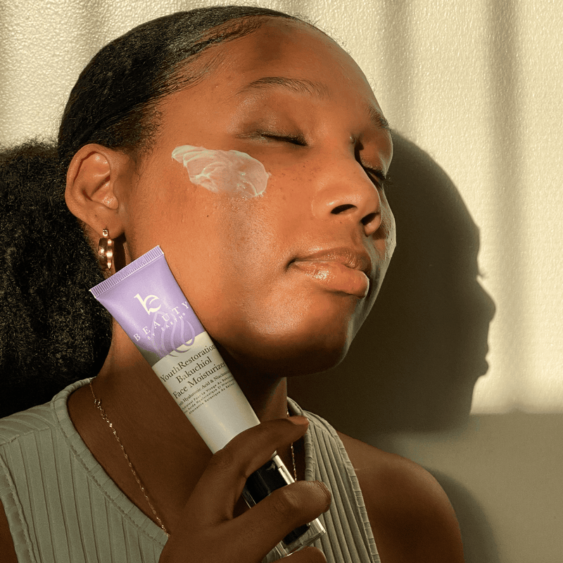 Woman applying skincare product to her face with a tube of cream.