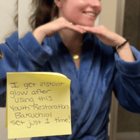 Person wearing a blue robe with a yellow sticky note on a mirror