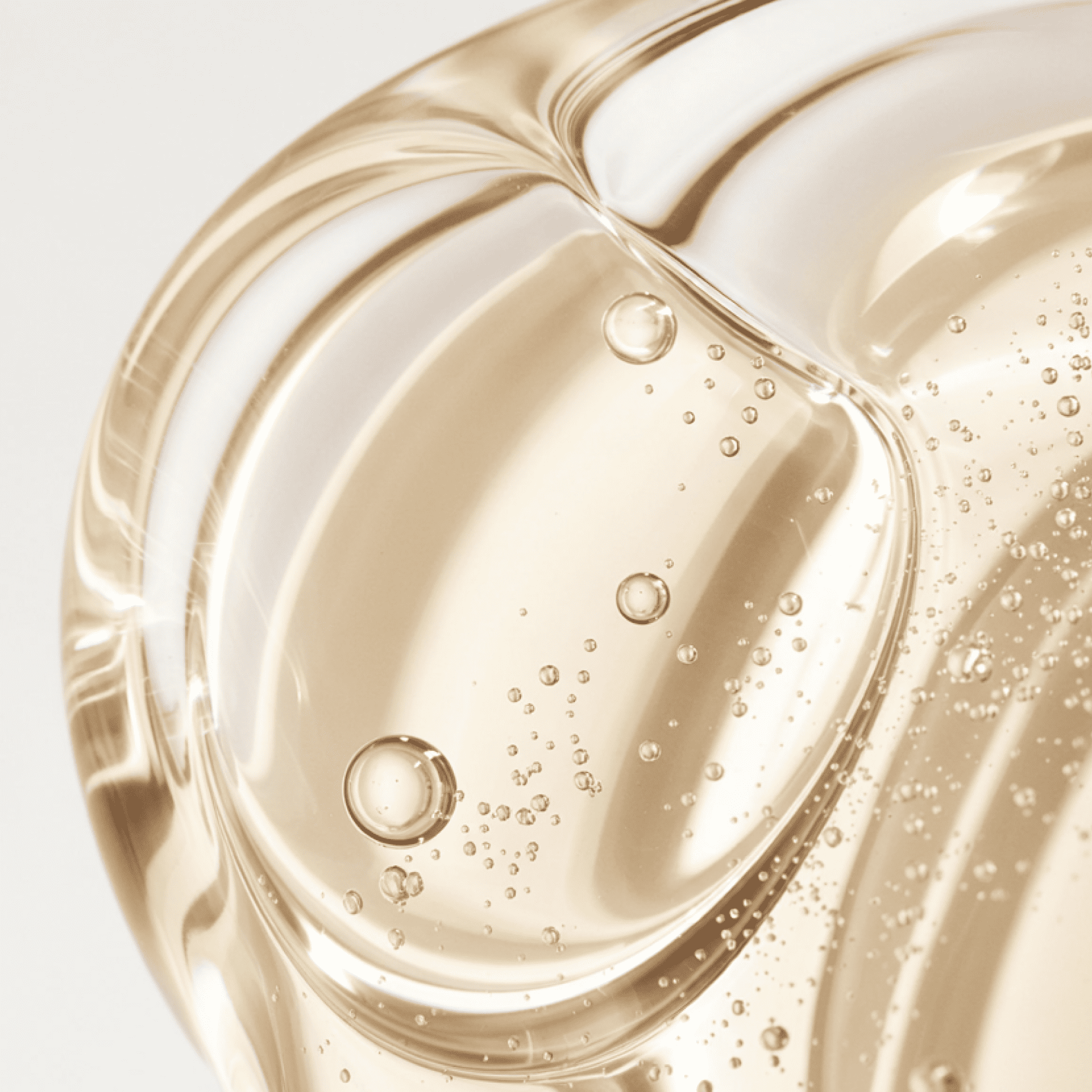 Close-up of a golden liquid with bubbles on a light gray background