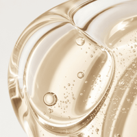 Close-up of a golden liquid with bubbles on a light gray background