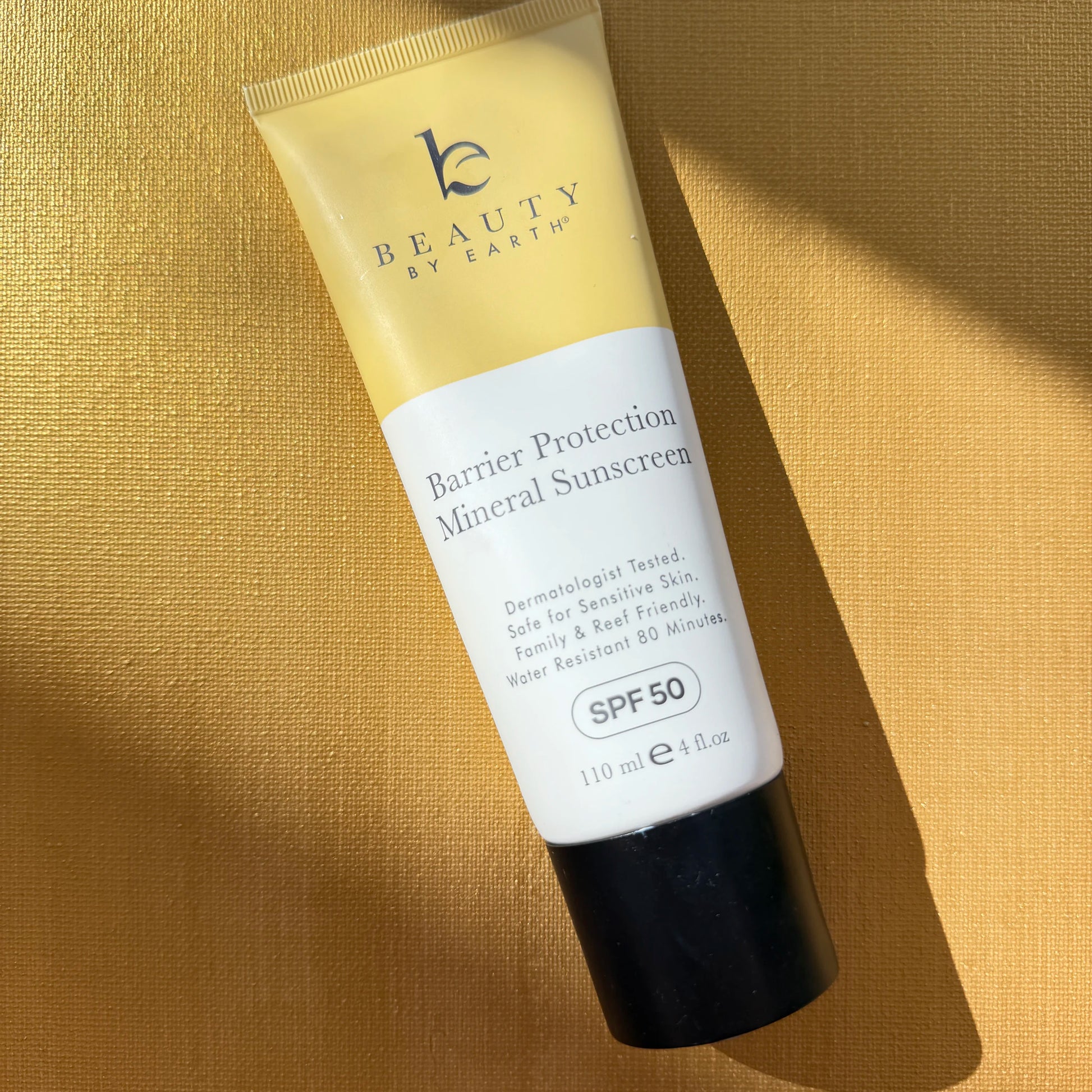 Tube of 'Beauty by Earth' Barrier Protection Mineral Sunscreen on a beige background