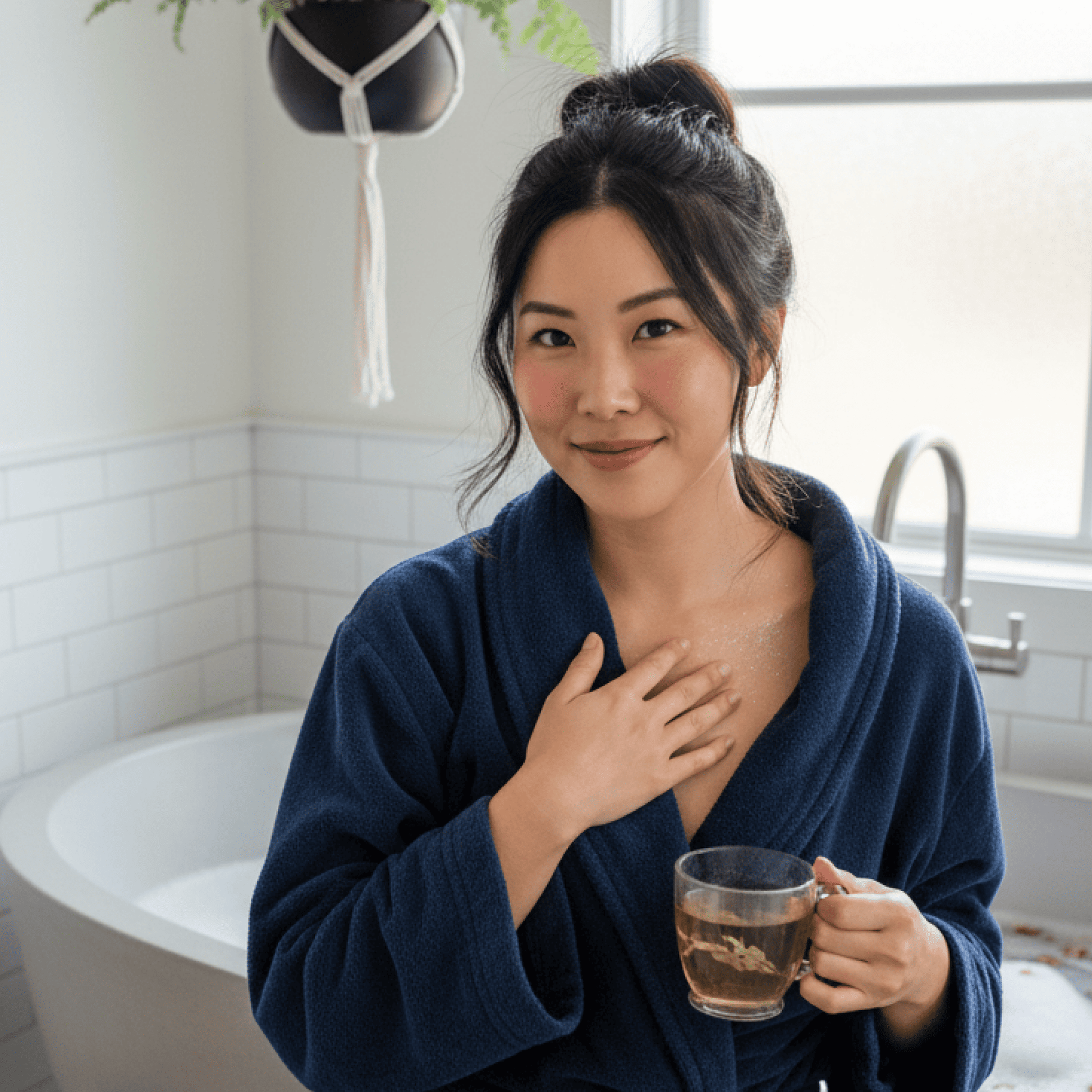 A woman in the bathroom feeling relaxed after taking a bath with bath bombs with tea in her hand