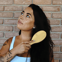 Woman brushing her hair against a brick wall background
