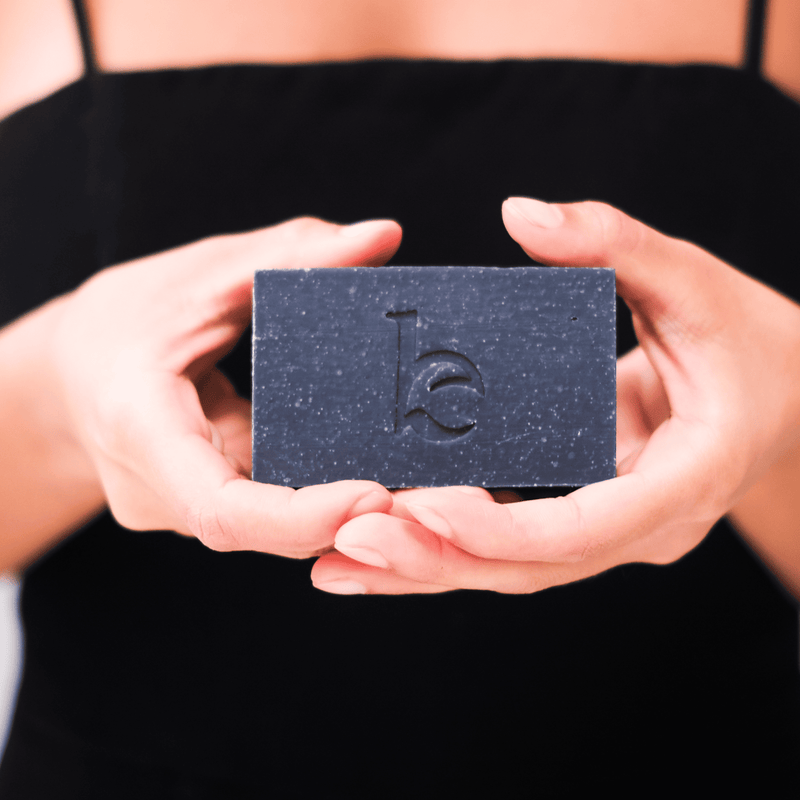 A model holding bar of charcoal soap in both hands macro 