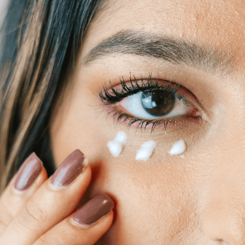 Close-up of a woman's eye with coffee bean eye cream under her eye
