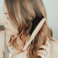 Woman brushing her hair with a wooden comb