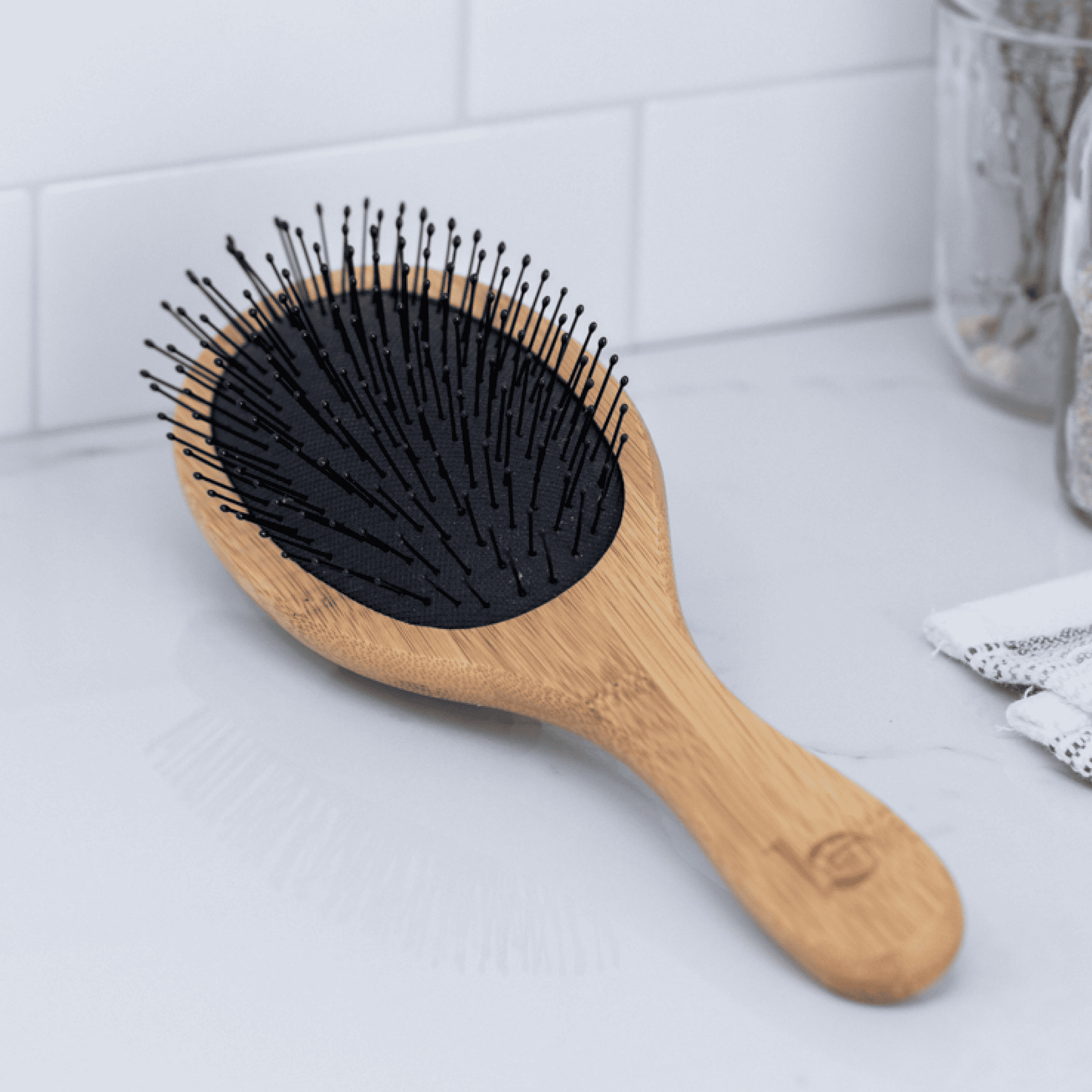 Wooden hairbrush with black bristles on a light gray surface.
