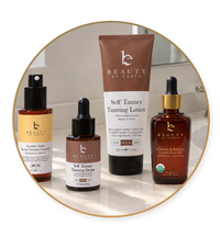 Four BEAUTY BY EARTH skincare products arranged inside a circular frame: a tanning lotion tube, a tanning drops bottle, a visible matte tanning wax bottle, and a cleansing & brightening facial oil in an amber glass bottle.