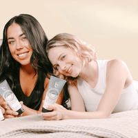 Two women holding clay face mask tubes in hands