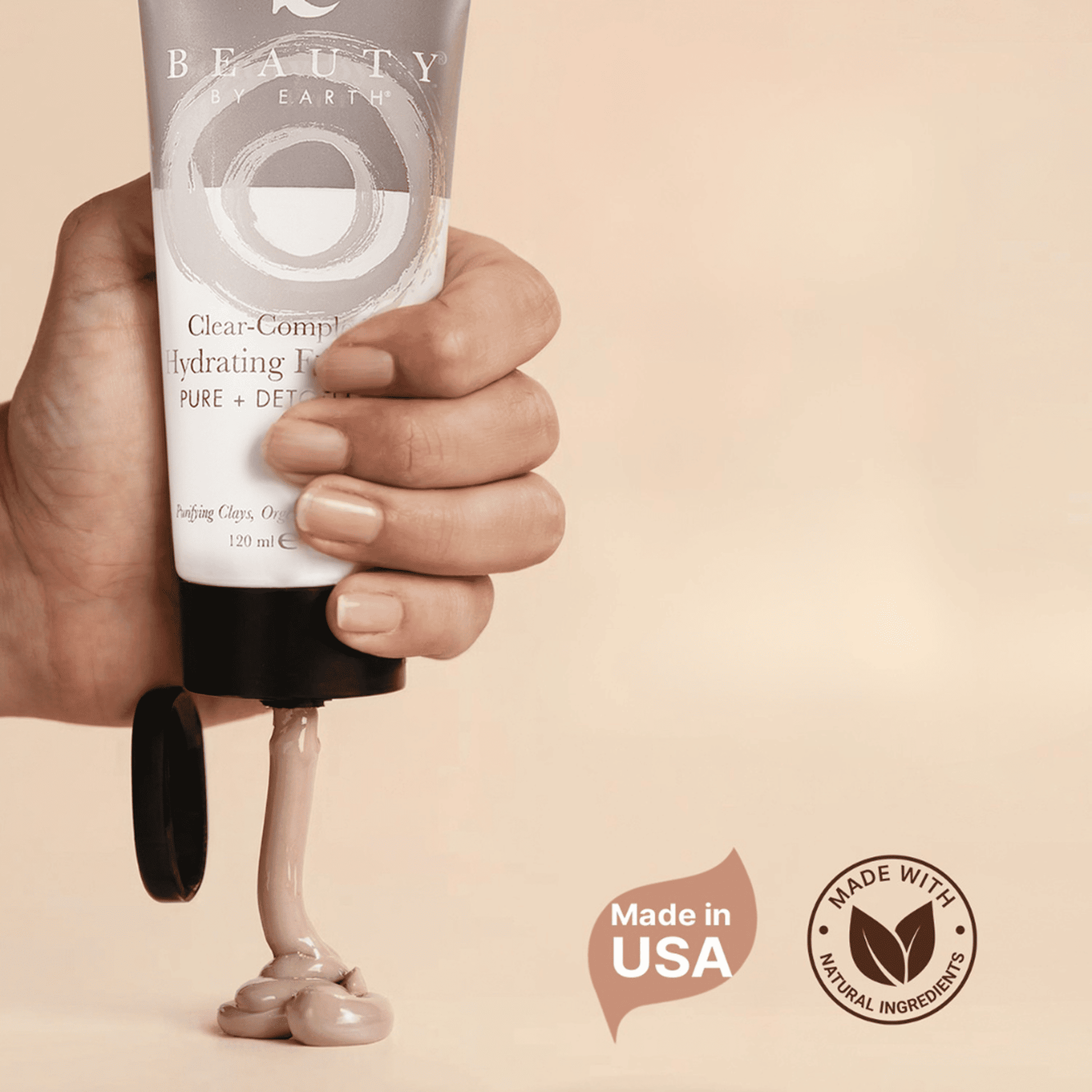 Hand squeezing clay face mask on surface - made in USA with natural ingredients.