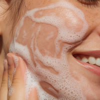 Person applying foamy cleanser to their face