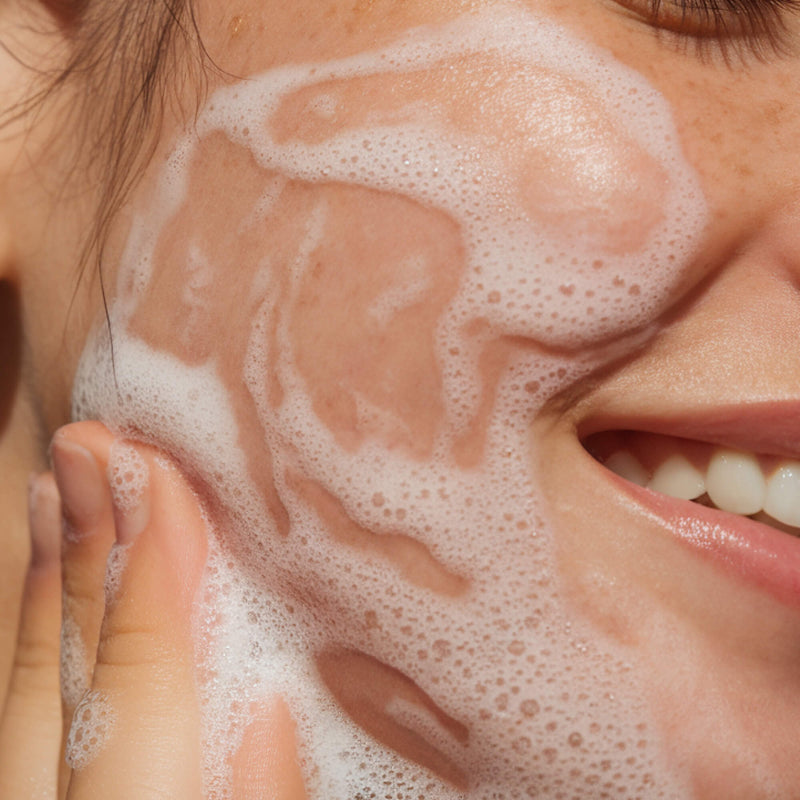 Person applying foamy cleanser to their face