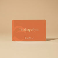 Orange card with 'Thinking of you' text and 'Beauty by Earth' logo on a beige background