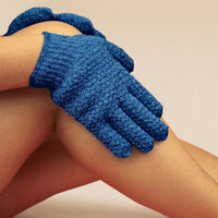 Blue exfoliating glove on a person's hand against a beige background