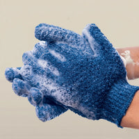 Blue exfoliating glove with soap suds on a beige background