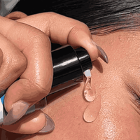 Hand applying a clear gel  to skin with a dropper.