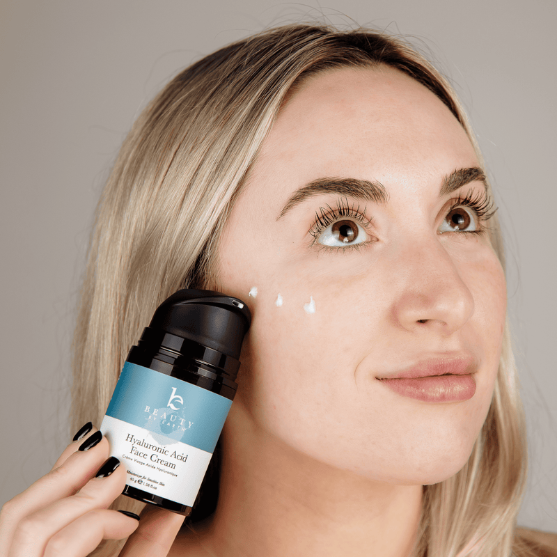 Woman applying skincare cream to her face with a visible brand label.