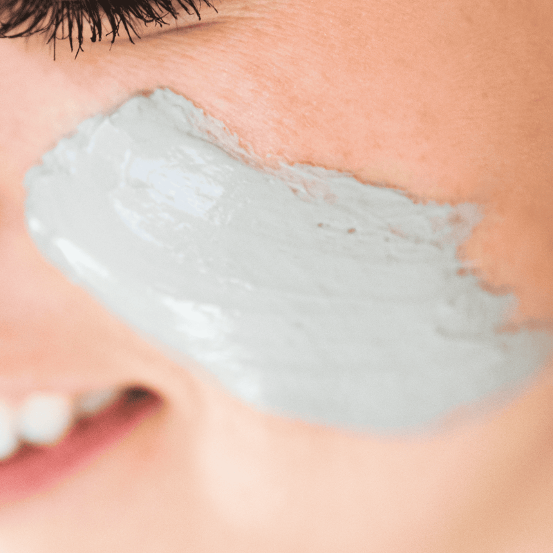 Close-up of a person applying gray cream to their face
