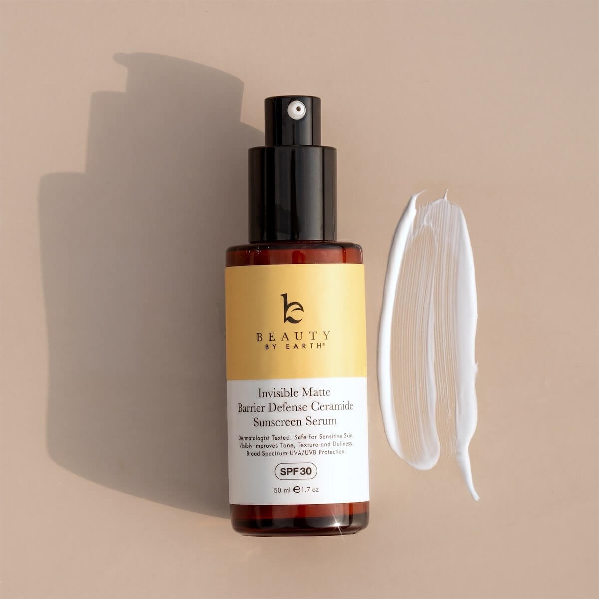 Sunscreen serum bottle with a smear of product on a beige background