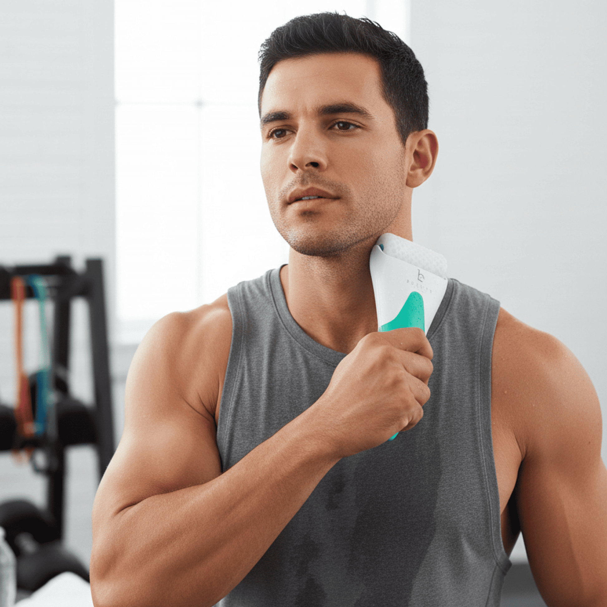 Man holding a white and green ice roller in a gym setting