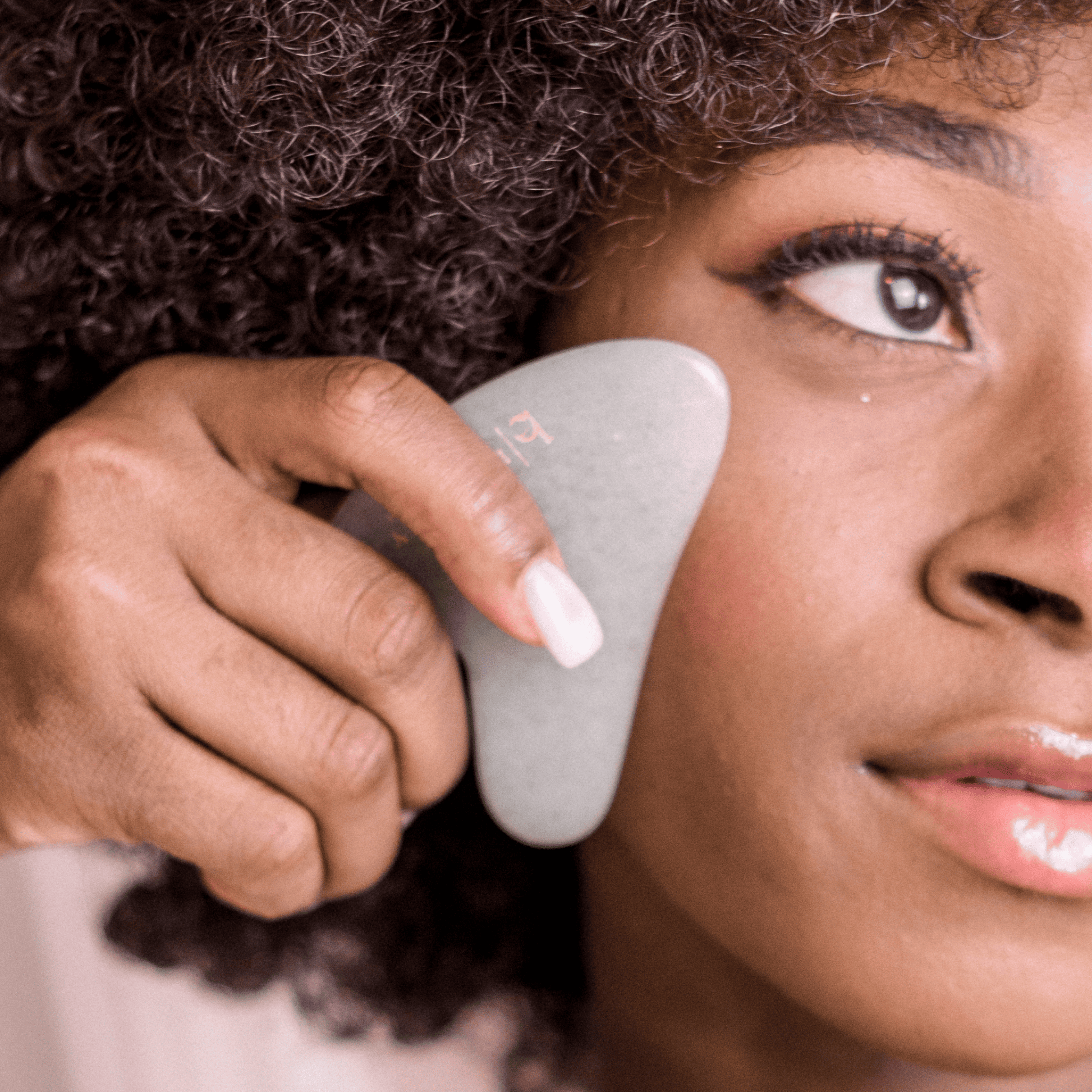 Person using a skincare jade gua sha tool on their face
